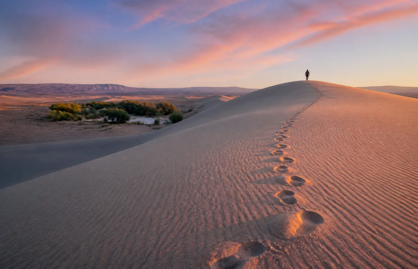 Marche au lever du soleil dans les dunes de Chegaga, oasis en contrebas